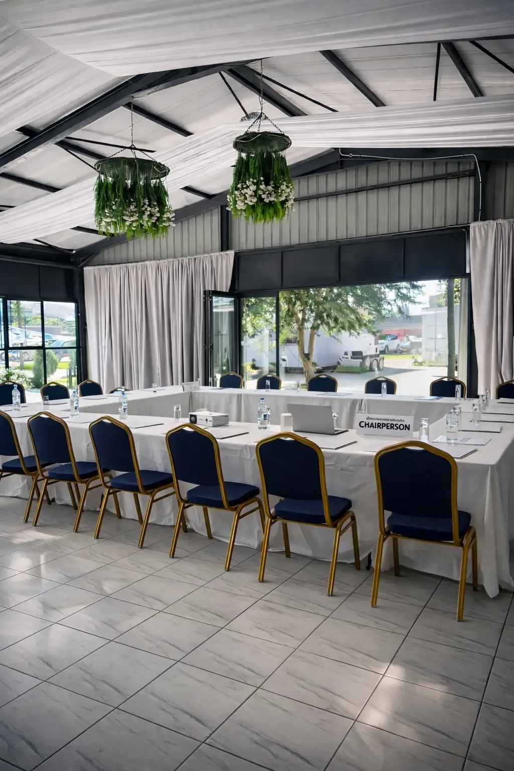 Light-filled corporate meeting space with white table linens and blue and gold chairs